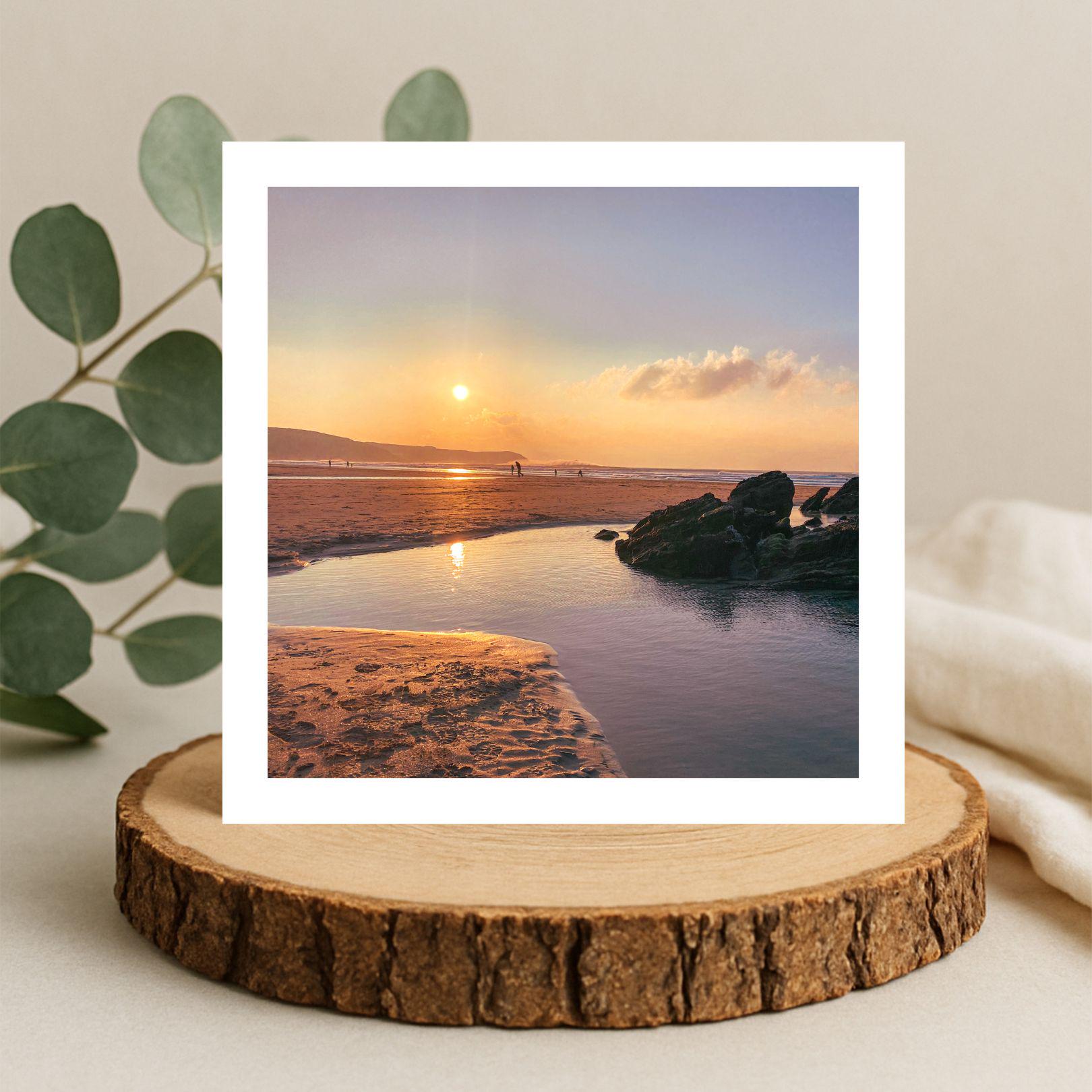 Greetings card of a sunset over rock pools on a wooden stand with a plant.
