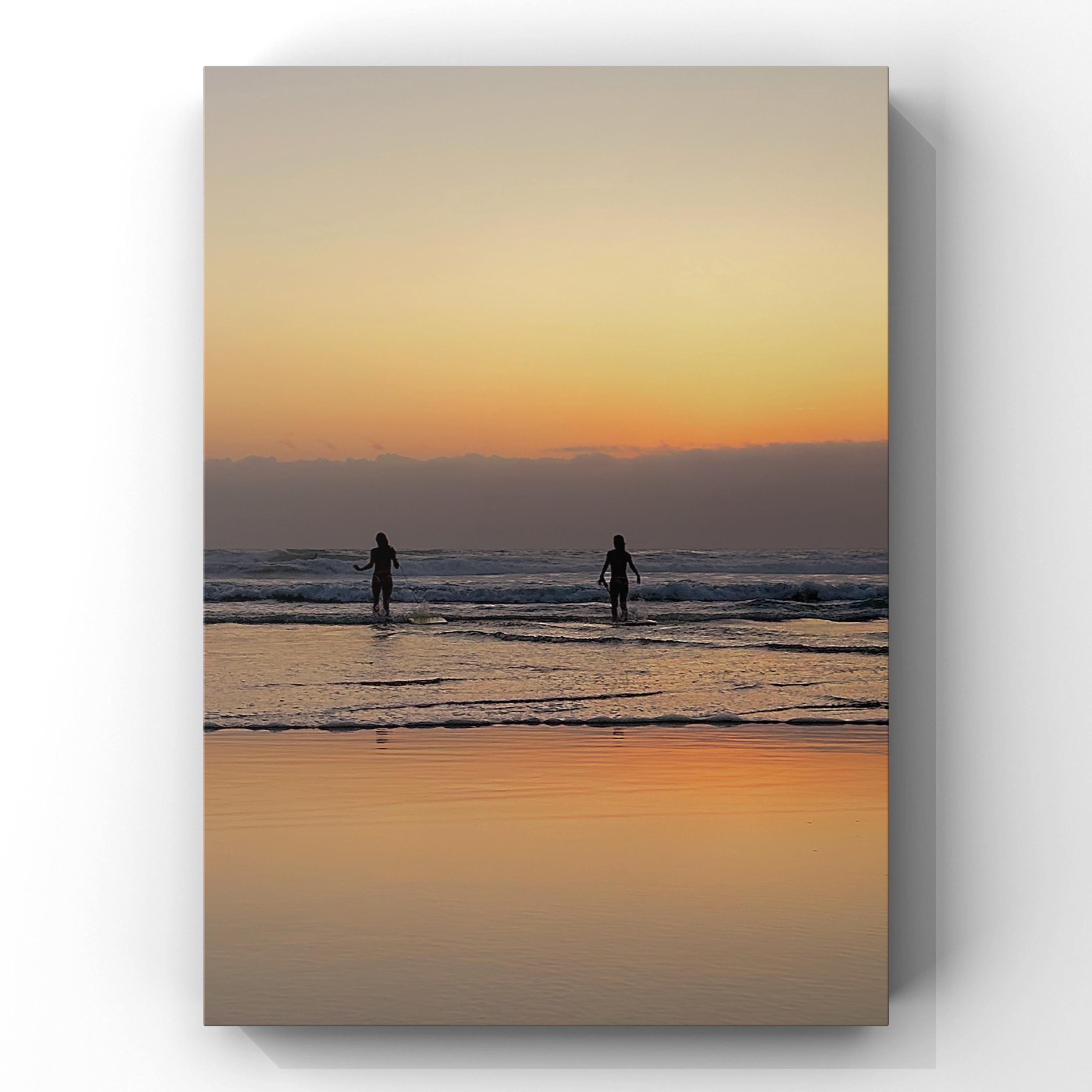 Two people going for a swim in the sea at sunset