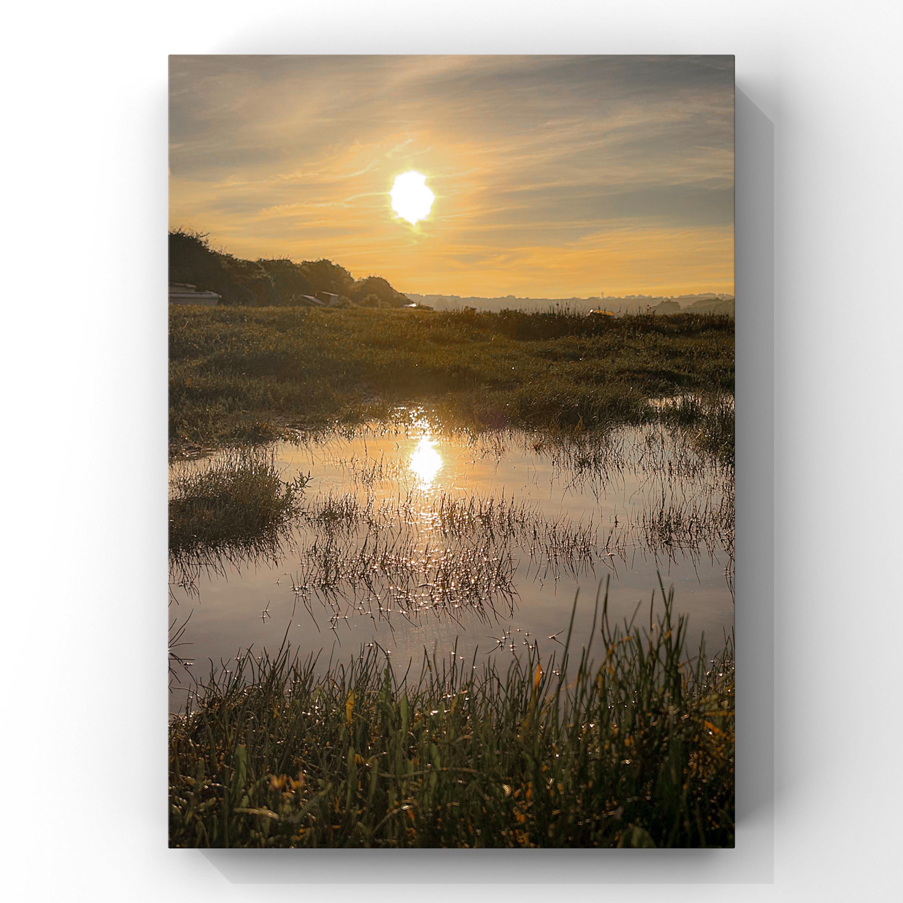 Sunrise over a marsh with water reflecting the orange sky