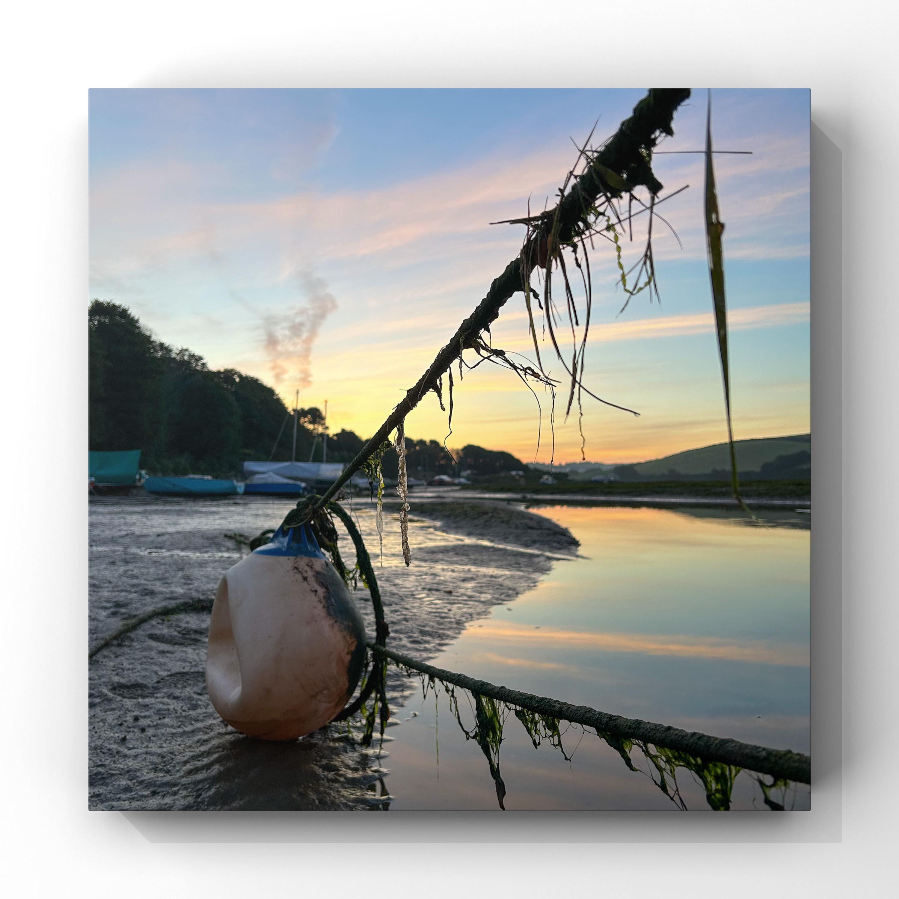 Ropes and mooring buoy on a beach at sunrise.
