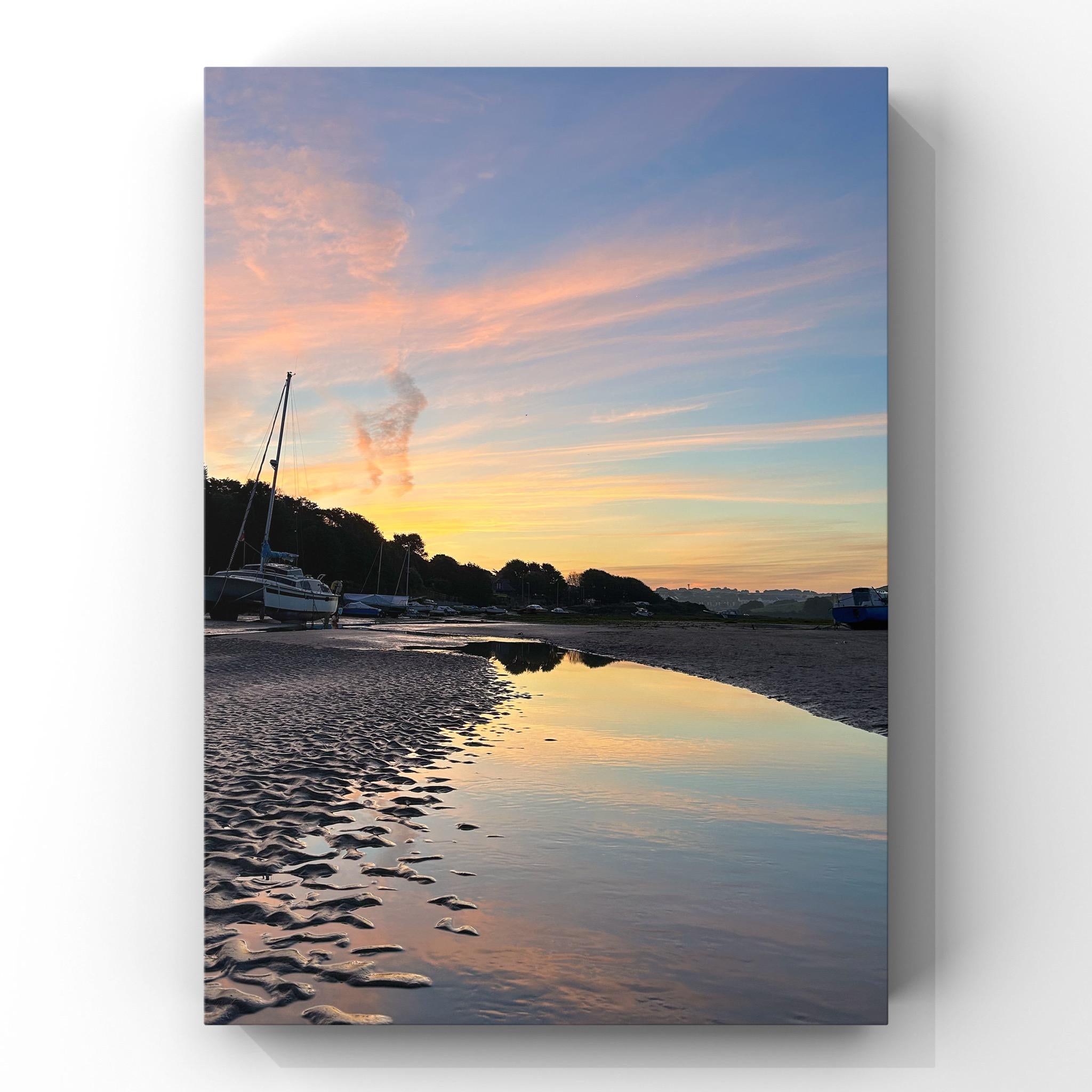 Beach scene with boats and a colorful sunrise sky reflected in water