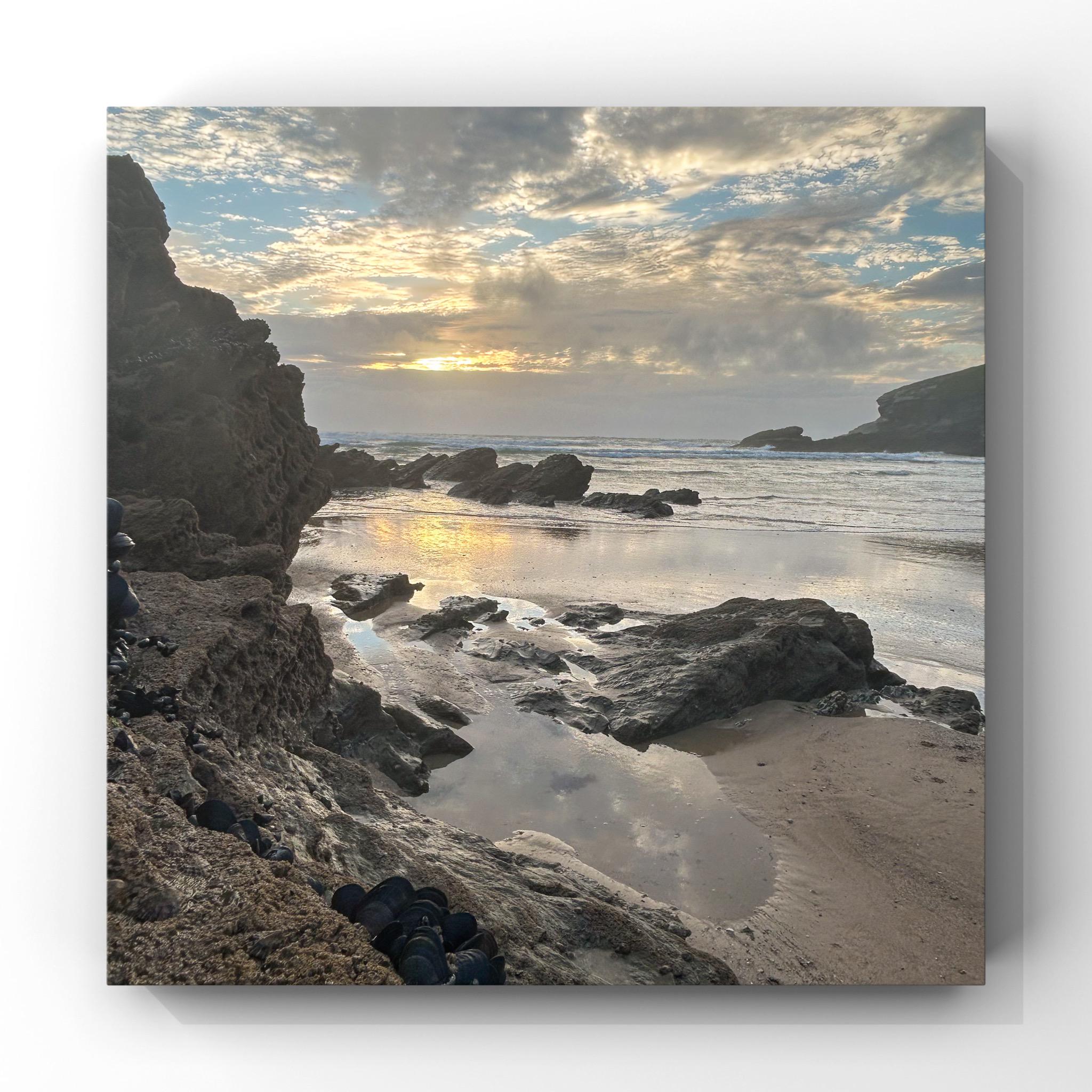 Beach scene with rocks and water at sunset