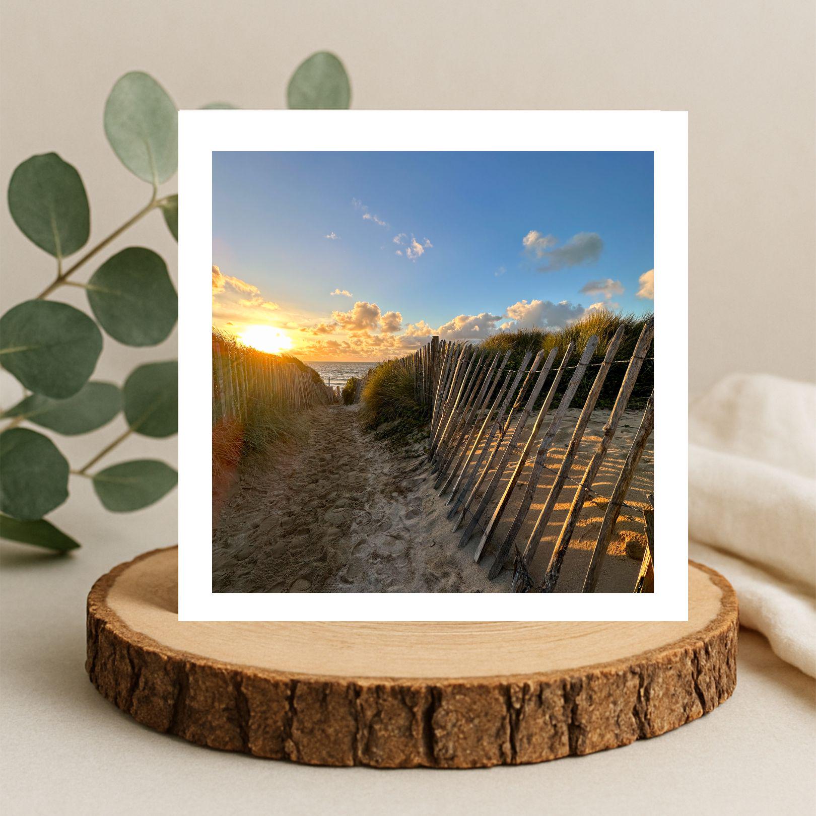 Greetings card with a sunset over a sandy path with wooden fences on a wooden stand.