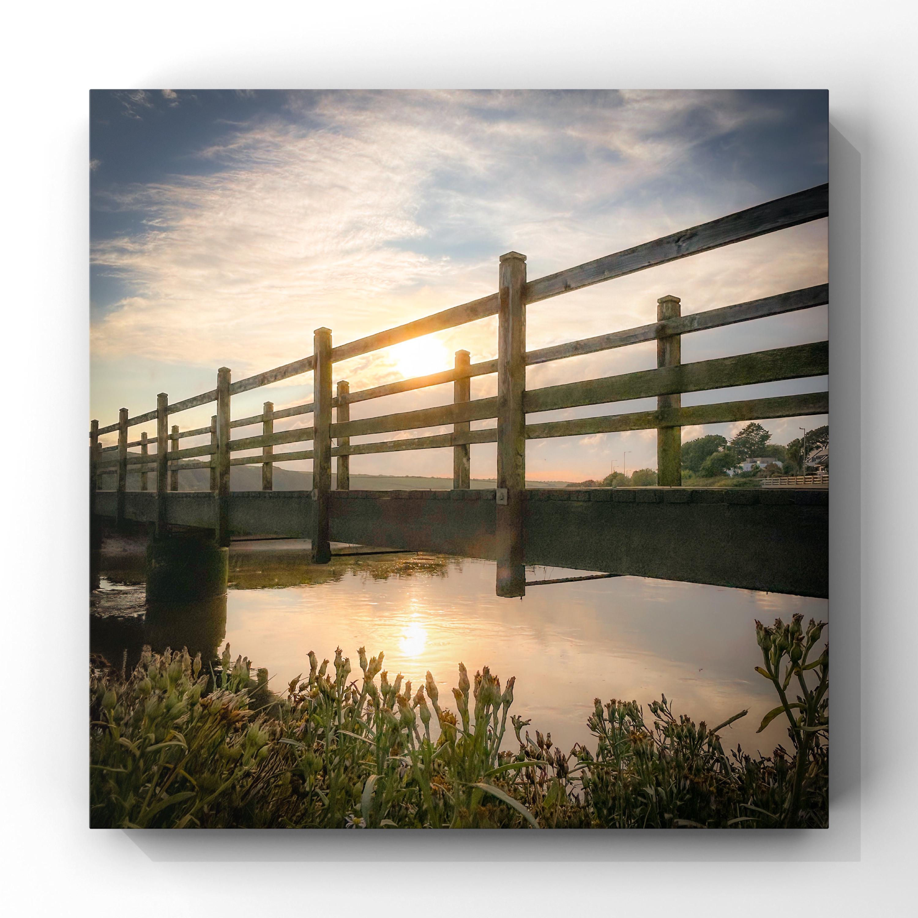 Wooden bridge over water with sunset in the background