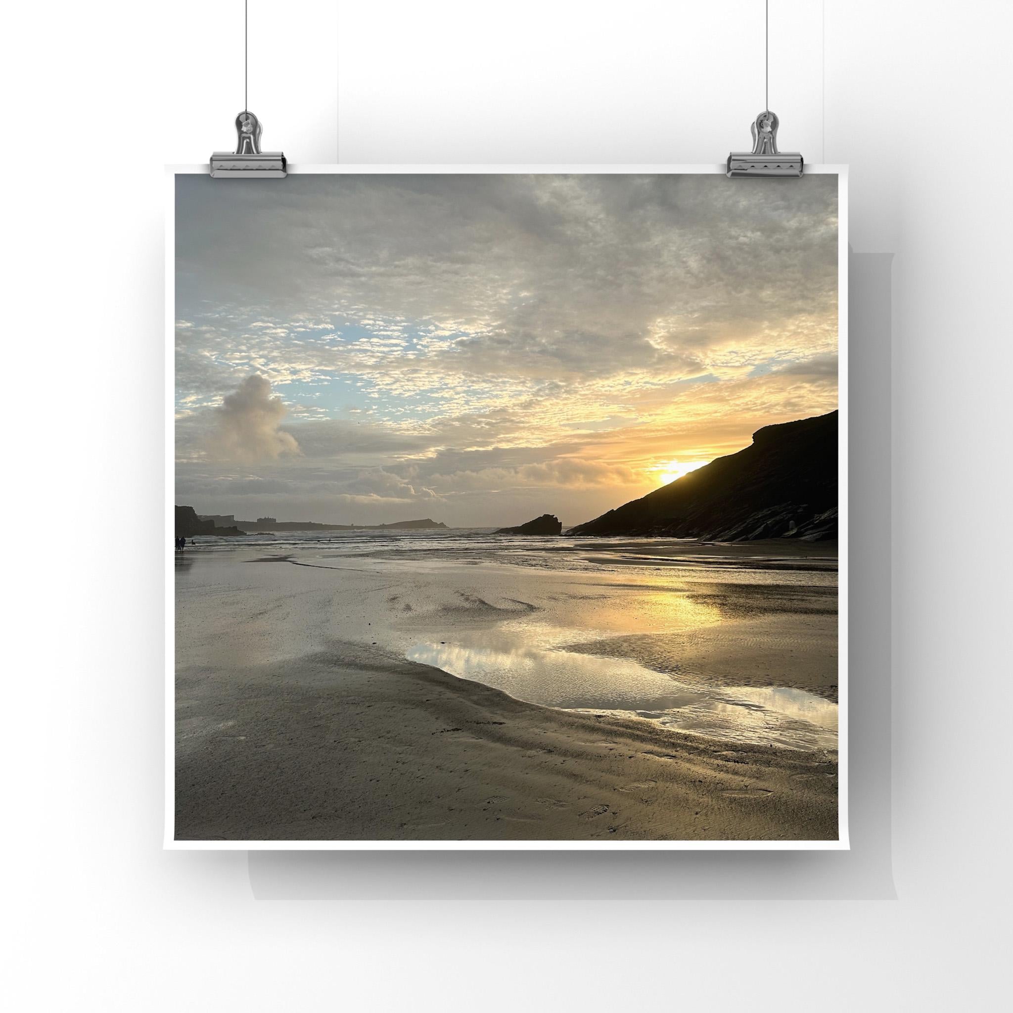 Sunset beach scene with sunset reflected in wet sand over a silhouetted headland, framed by a white border.
