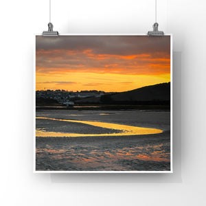 Sunrise over a coastal landscape with a curved reflected orange stream of water.