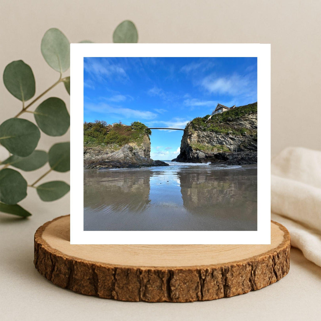 Card with a scenic view of a coastal landscape with a bridge over water, displayed on a wooden stand.