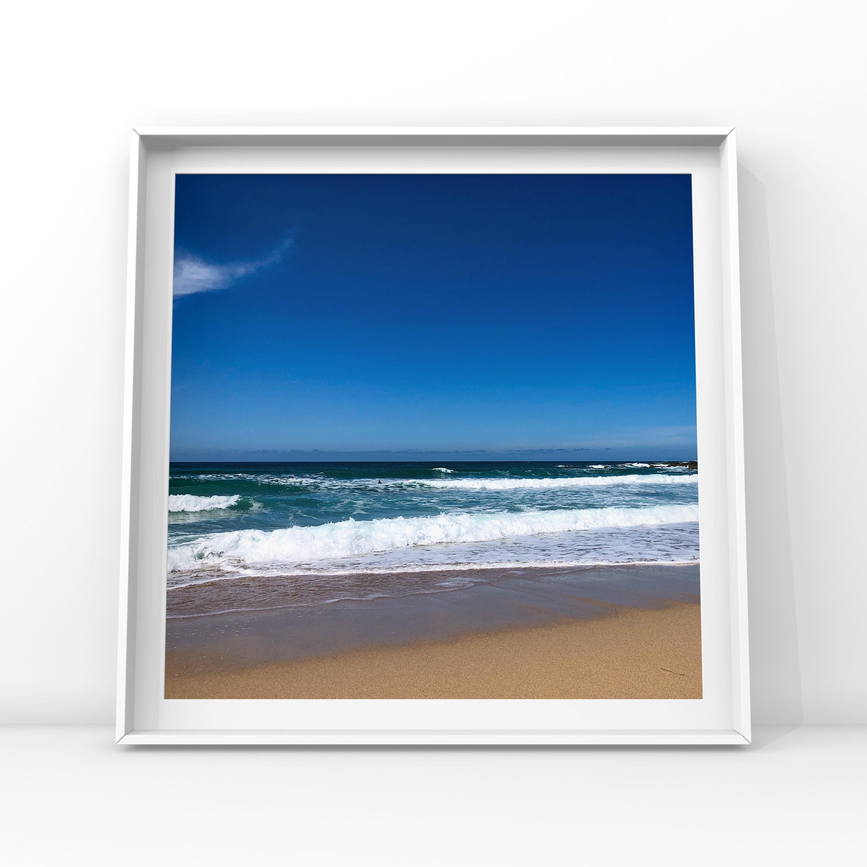 Framed photograph of a beach scene with blue sky and ocean.