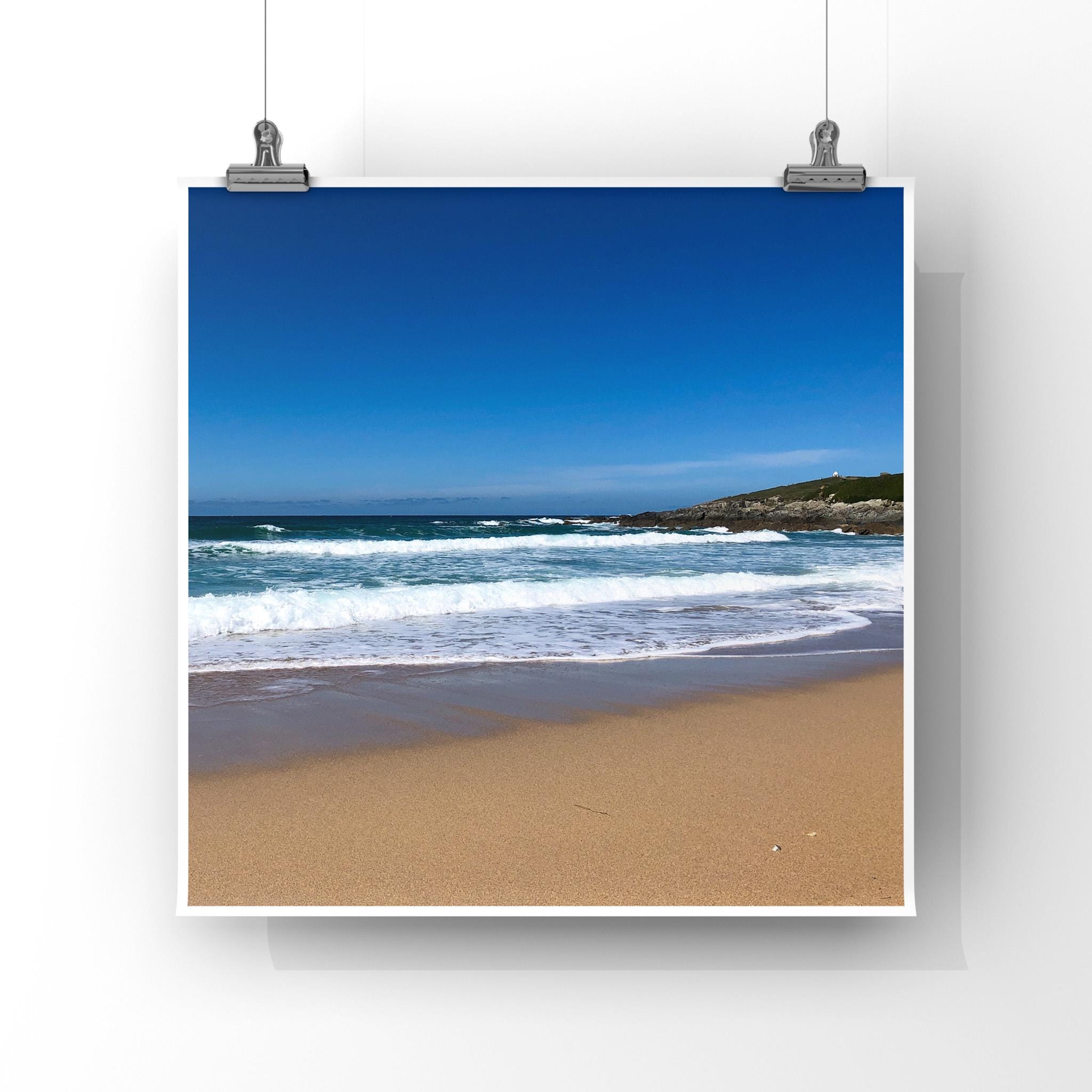 Beach scene with blue sky, ocean waves, and sandy shore.